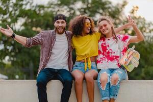 feliz jovem companhia do sorridente amigos sentado dentro parque foto