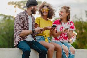 feliz jovem companhia do sorridente amigos sentado dentro parque foto