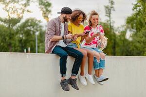 feliz jovem companhia do sorridente amigos sentado dentro parque foto