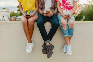 feliz jovem companhia do sorridente amigos sentado dentro parque foto