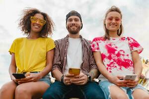 feliz jovem companhia do sorridente amigos sentado dentro parque foto