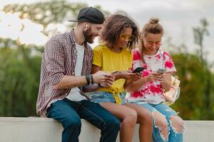 feliz jovem companhia do sorridente amigos sentado dentro parque foto