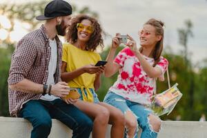 feliz jovem companhia do sorridente amigos sentado dentro parque foto