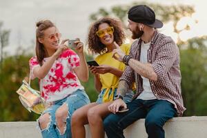 feliz jovem companhia do sorridente amigos sentado dentro parque foto