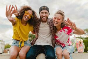 feliz jovem companhia do sorridente amigos sentado dentro parque foto