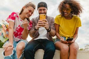 feliz jovem companhia do sorridente amigos sentado dentro parque foto