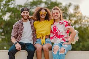 feliz jovem companhia do sorridente amigos sentado dentro parque foto