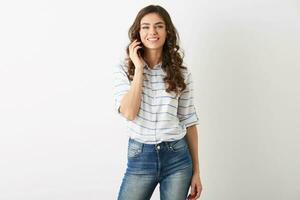 bonita mulher hipster estilo aluna equipamento falando em Smartphone, sorridente olhando dentro Câmera, atraente modelo usando Móvel telefone, casual roupa, saiu face expressão, isolado, comunicação foto