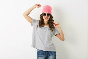 hipster bonita mulher dentro Rosa chapéu, oculos de sol, dançando feliz, sorridente face, grandes cabelo, positivo humor, emocional, hipster estilo roupa, verão moda tendência, jeans e listrado camiseta, isolado foto