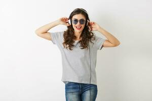 jovem atraente mulher ouvindo para música em fones de ouvido, vestindo oculos de sol, isolado em branco fundo, foto