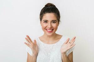 retrato do jovem sincero sorridente mulher dentro branco blusa, positivo surpreso face expressão, feliz, segurando mãos acima, aberto Palmeiras, isolado em estúdio fundo foto