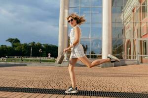 jovem atraente à moda mulher corrida pulando engraçado dentro tênis dentro cidade rua foto