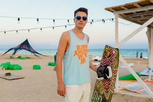 jovem Atlético homem com pipa surfar borda posando em de praia vestindo oculos de sol em verão férias, ativo Esportes passatempo foto