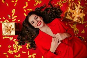 atraente mulher a comemorar Natal em vermelho fundo dentro confete foto