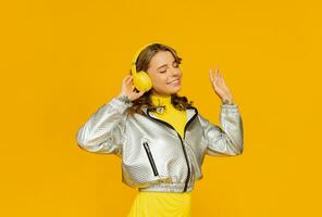 sorridente atraente mulher ouvindo para música dentro fones de ouvido em amarelo fundo foto