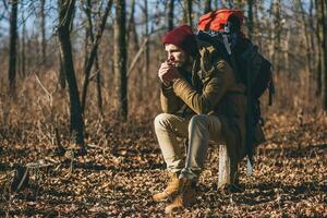 jovem hipster homem viajando com mochila dentro Primavera outono floresta foto