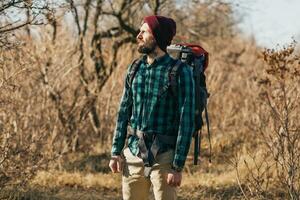 jovem hipster homem viajando com mochila dentro Primavera outono floresta foto