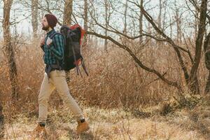 jovem hipster homem viajando com mochila dentro Primavera outono floresta foto