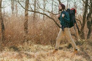 jovem hipster homem viajando com mochila dentro Primavera outono floresta foto