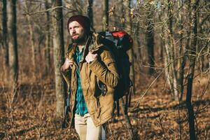 jovem hipster homem viajando com mochila dentro Primavera outono floresta foto