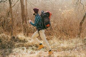 jovem hipster homem viajando com mochila dentro Primavera outono floresta foto