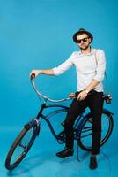 jovem bonito sorridente feliz homem viajando em hipster bicicleta foto