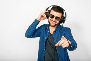 jovem bonito feliz sorridente homem dançando e ouvindo para música dentro fones de ouvido foto