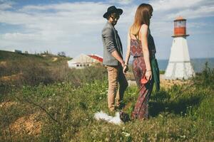 Visão a partir de costas em jovem à moda hipster casal dentro amor caminhando com cachorro dentro campo foto