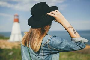 jovem mulher dentro natureza, farol jeans jaqueta, Preto chapéu, verão, à moda acessórios foto