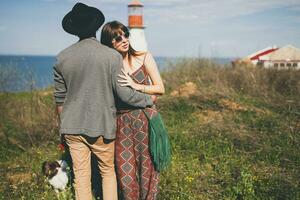 jovem à moda hipster casal dentro amor caminhando com cachorro dentro campo foto