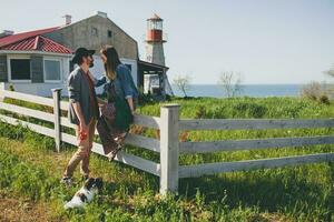 jovem à moda hipster casal dentro amor caminhando com cachorro dentro campo foto