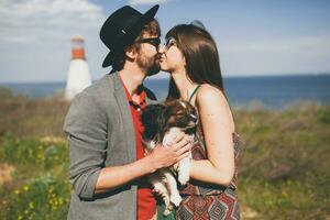 adorável sorridente jovem à moda hipster casal dentro amor caminhando com cachorro dentro campo foto