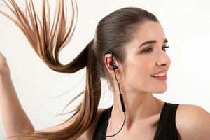 atraente mulher dentro corrida Preto topo ouvindo para música em fones de ouvido foto