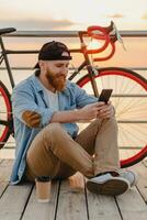 jovem barbudo homem viajando em bicicleta às pôr do sol mar foto