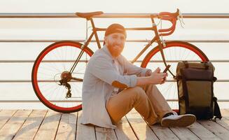 jovem barbudo homem viajando em bicicleta às pôr do sol mar foto