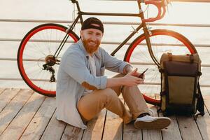 jovem barbudo homem viajando em bicicleta às pôr do sol mar foto