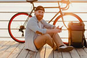 jovem barbudo homem viajando em bicicleta às pôr do sol mar foto