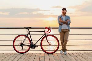 bonito barbudo homem viajando com bicicleta dentro manhã nascer do sol de a mar foto