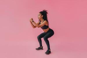 atraente Preto africano americano mulher dentro Preto leggins ginástica equipamento em Rosa fundo foto