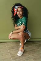 atraente Preto africano americano mulher posando dentro à moda hipster equipamento em verde fundo foto