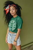 atraente Preto africano americano mulher posando dentro à moda hipster equipamento em verde fundo foto