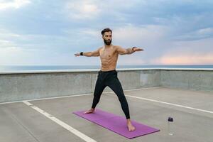 atraente hansome homem com Atlético Forte corpo fazendo manhã ioga asana ao ar livre foto