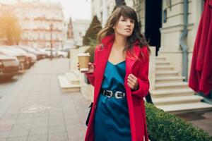 à moda mulher dentro vermelho casaco caminhando dentro rua com café foto