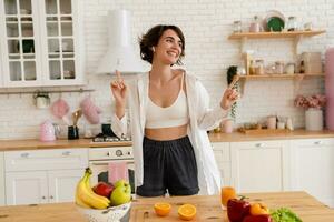 jovem bonita mulher cozinhando às lar, manhã cozinha, saudável Comida foto