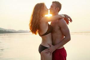 jovem sexy romântico casal dentro amor feliz em verão de praia juntos tendo Diversão vestindo nadar ternos foto