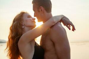 jovem sexy romântico casal dentro amor feliz em verão de praia juntos tendo Diversão vestindo nadar ternos foto