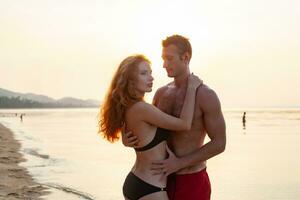 jovem sexy romântico casal dentro amor feliz em verão de praia juntos tendo Diversão vestindo nadar ternos foto