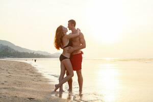 jovem sexy romântico casal dentro amor feliz em verão de praia juntos tendo Diversão vestindo nadar ternos foto