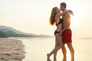 jovem sexy romântico casal dentro amor feliz em verão de praia juntos tendo Diversão vestindo nadar ternos foto