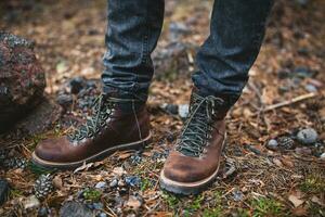 pernas dentro sapatos do jovem hipster homem caminhada dentro montanhas foto